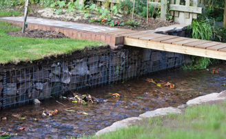 Garden project reclaiming lawn and elegantly restraining small river